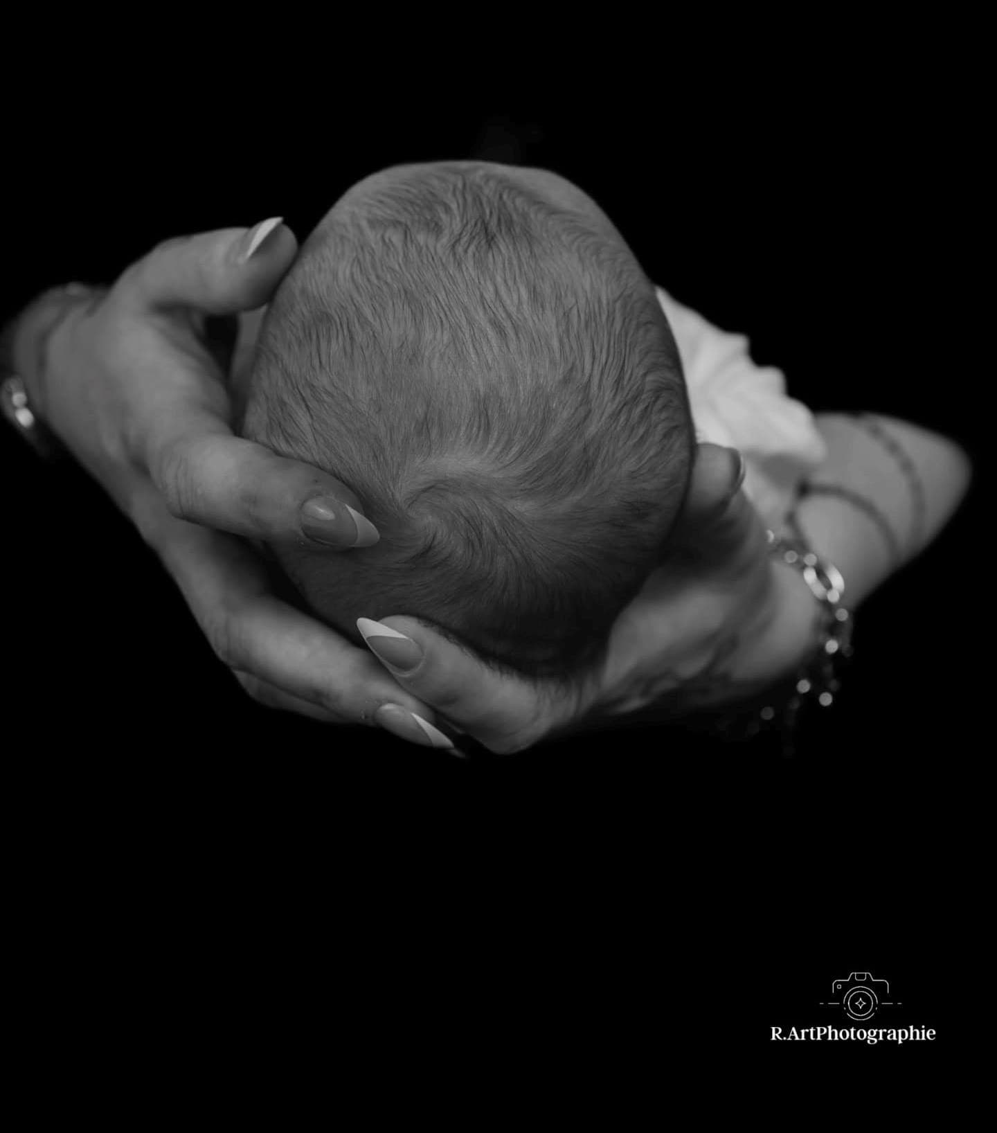 Newborn Shooting in Kaufbeuren: schlafendes Neugeborenes wird in den Händen der Eltern gehalten